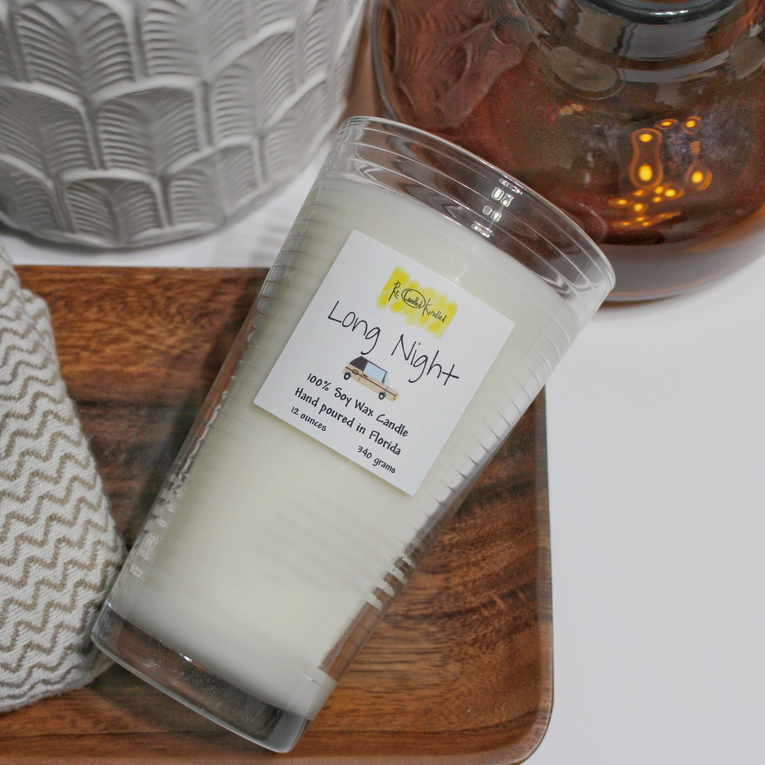 Twelve ounce candle poured in an upcycled pint drinking glass. The scent is Long Night and it's titled on its side to see a clear view of the label.